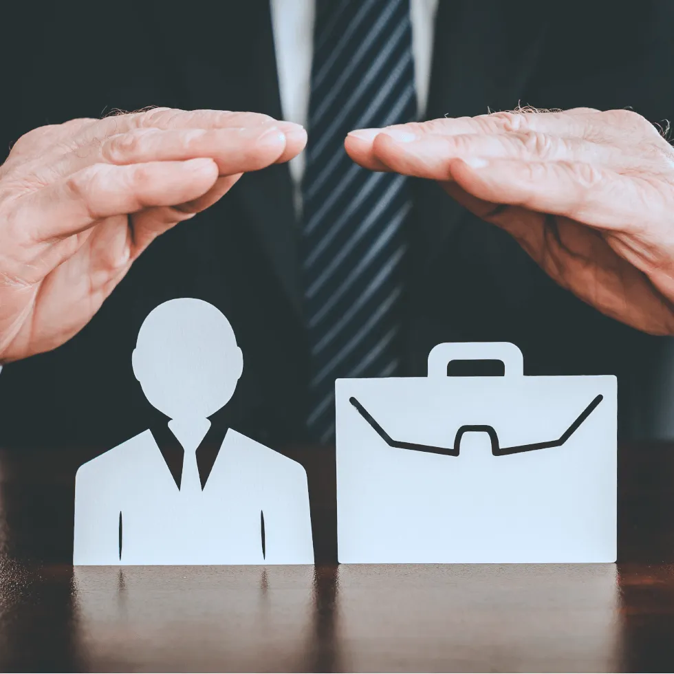 insurance-agent-placing-hands-protectively-over-paper-model-of-businessman